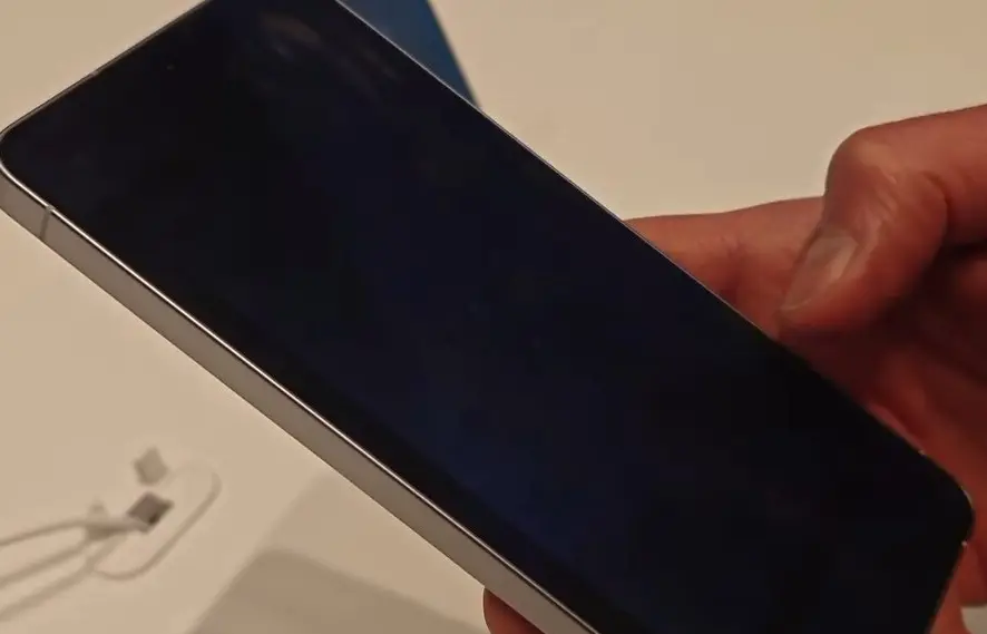 A phone held at an angle with a privacy display switched on: from the side the screen looks black
